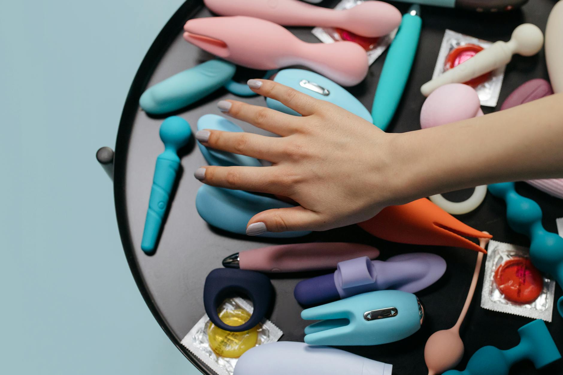 Una mano che tiene un vibratore colore arancio su sfondo viola minimalista, che mostra la sensualità moderna