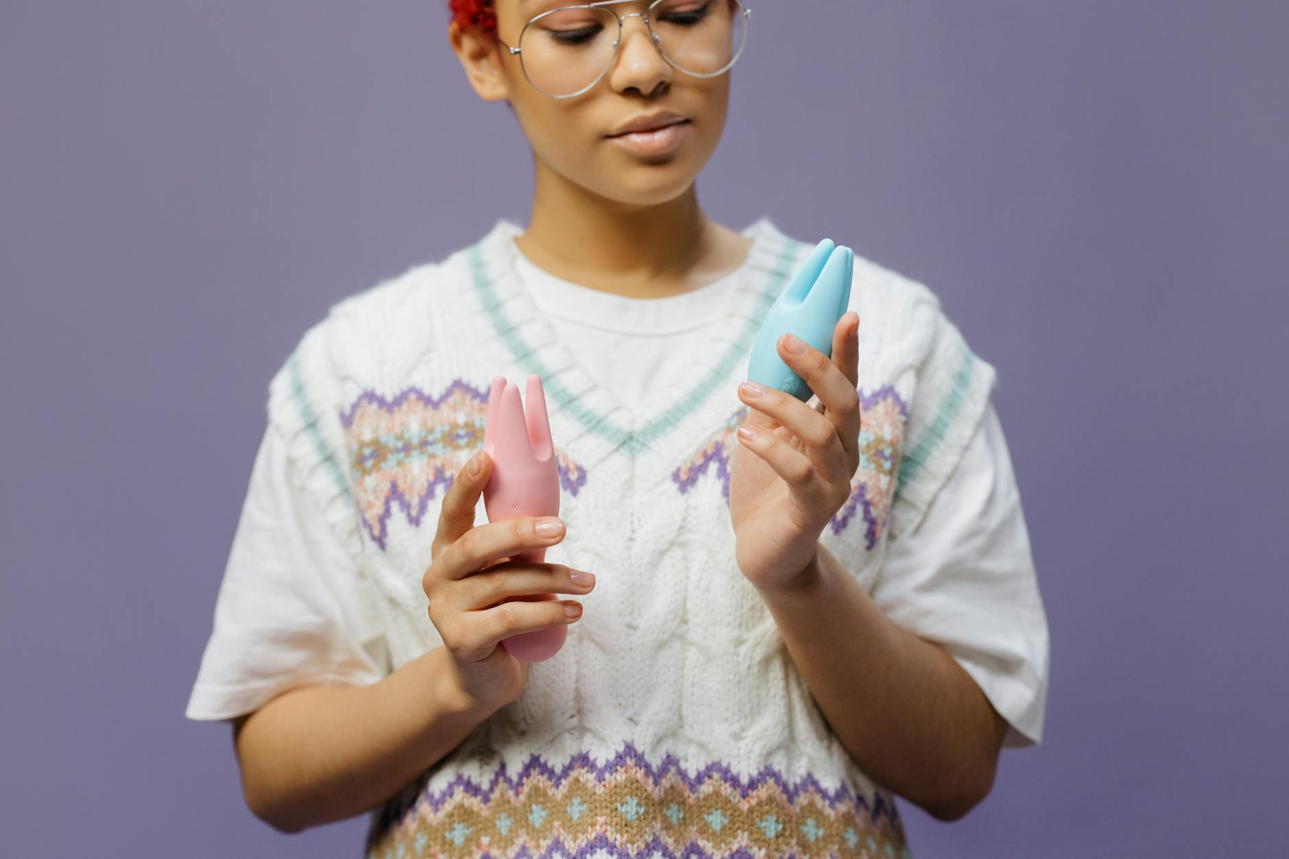 Donna che tiene in mano vibratori in silicone colorati con espressione consapevole